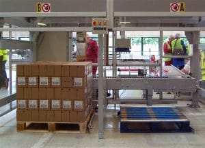 A pallet stacked full of boxes next to an empty pallet in a warehouse