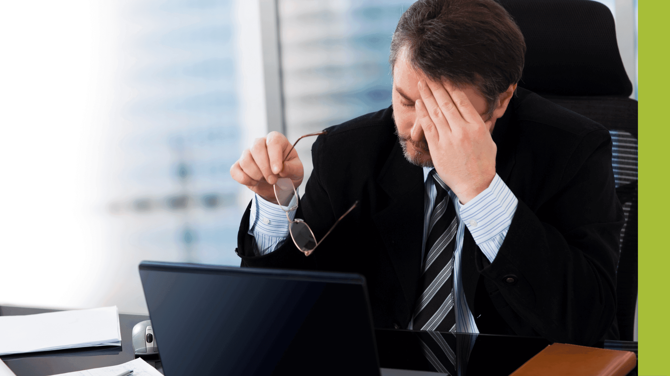 Businessman looking stressed looking at his screen and holding his glasses